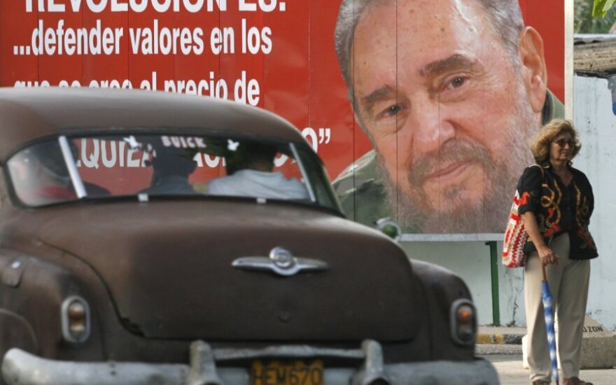Senas automobilis rieda pro buvusio Kubo lyderio Fidelio Castro portretą Havanoje.