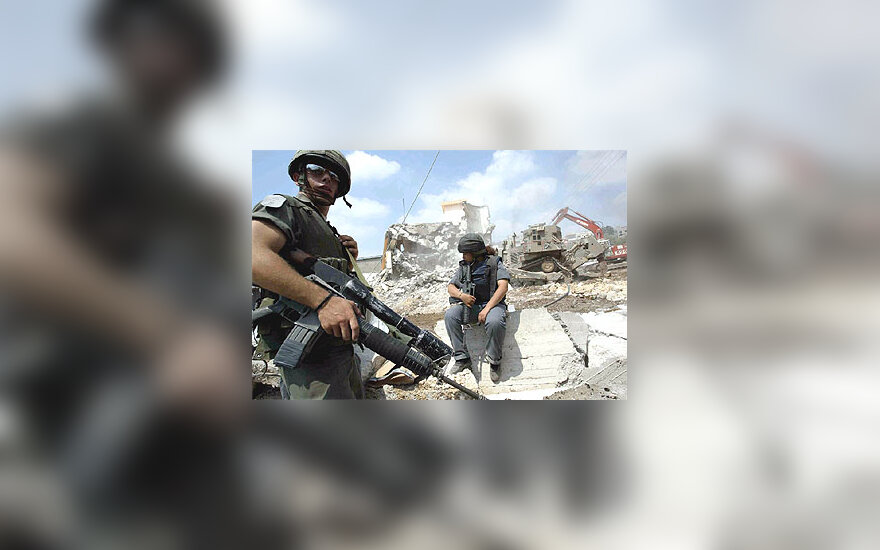 Izraelio kariai stebi griaunama palestiniečių namą