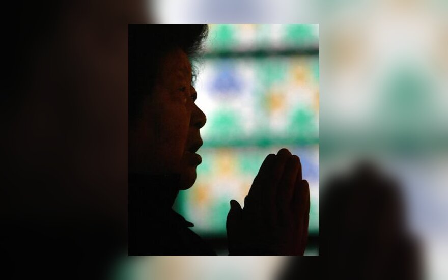Pekino bažnyčioje moteris meldžiasi už mirusį popiežių.