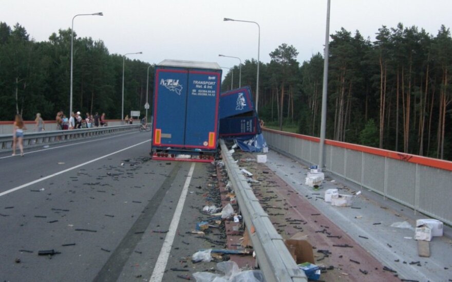 Girtas vilkiko vairuotojas gatvėje išbarstė krovinį ir apsivertė ant tilto