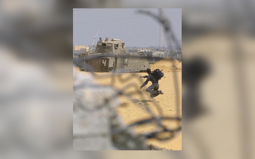 Palestiniečių jaunuolis meta akmenį į Izraelio armijos tanką