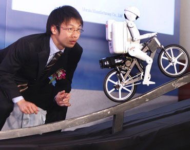 Kinų inžinierius stebi dviračiu važiuojantį humanoidinį robotuką