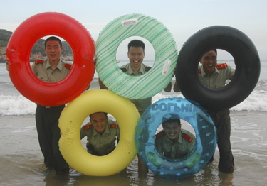 Apsaugos darbuotojai pozuoja su plaukimo ratais, simbolizuojančiais Olimpiados žiedus