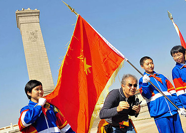Užsienio turistas pozuoja kartu su jaunaisiais Kinijos komunistų partijos nariais