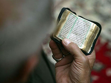 Besimeldžiantis vyras skaito iš mažos Korano kopijos