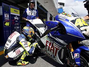 Italų lenktynininkas Valentino Rossi meldžiasi šalia savo motociklo prieš išvažiuodamas į trasą