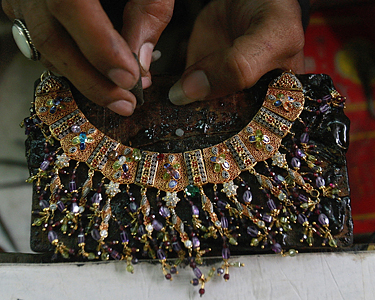 Pakistane juvelyras auksu dekoruoja vėrinį.