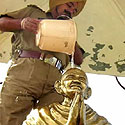Indų policininkas pila vandenį ant Mahatma Gandhi statulos