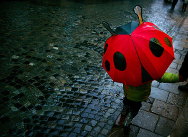 Mergaitė eina su boružės formos skėčiu Varšuvoje