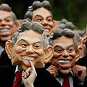 žmonės pozuoja fotografams užsidėję kaukes su Tony Blairo atvaizdu