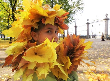 Sankt Peterburge mergaitė džiaugiasi spalvotais klevo lapais.