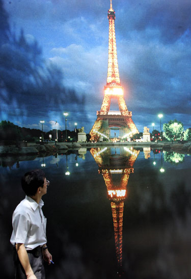 Vyras eina pro milžinišką ekraną su Eifelio bokšto atvaizdu Honkongo parke.