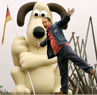 Animacinių filmų direktorius Nickas Parkas pozuoja šalia didžiulės Gromito figūros Miunchene.