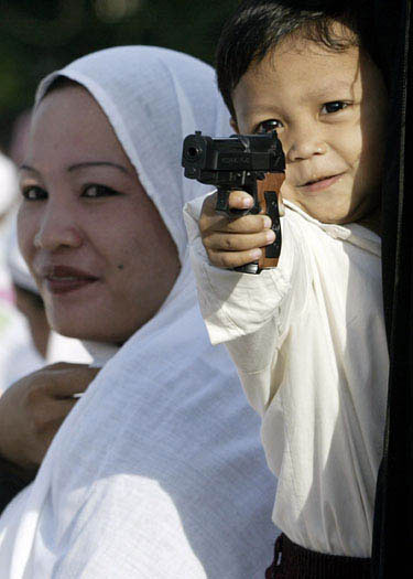 Filipinietis berniukas žaidžia su žaisliniu ginklu.
